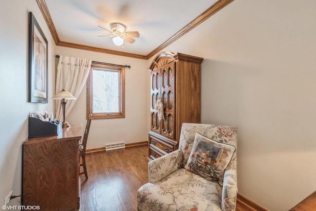 living area featuring a ceiling fan, visible vents, baseboards, ornamental molding, and dark wood finished floors