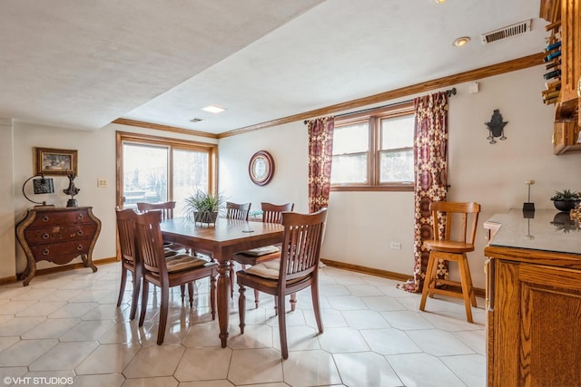 dining room featuring baseboards, visible vents, and ornamental molding