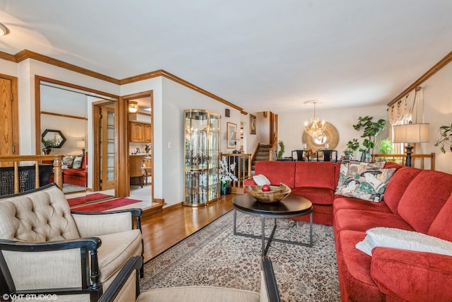 living room featuring a notable chandelier, stairs, crown molding, and wood finished floors