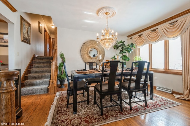 dining room with baseboards, visible vents, stairway, wood finished floors, and an inviting chandelier