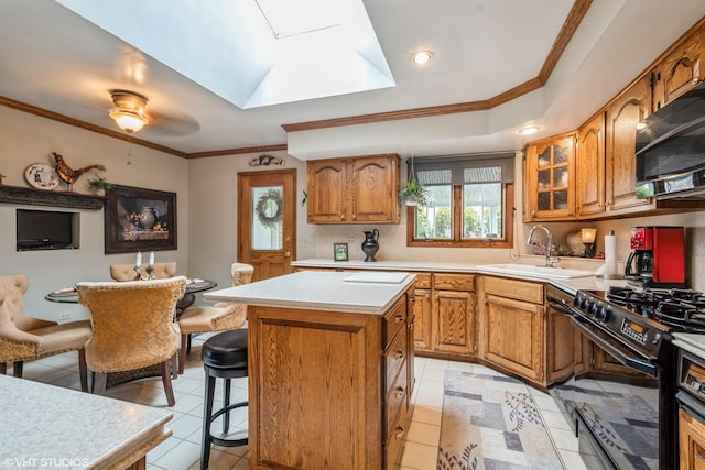 kitchen with a sink, light countertops, black appliances, brown cabinetry, and glass insert cabinets