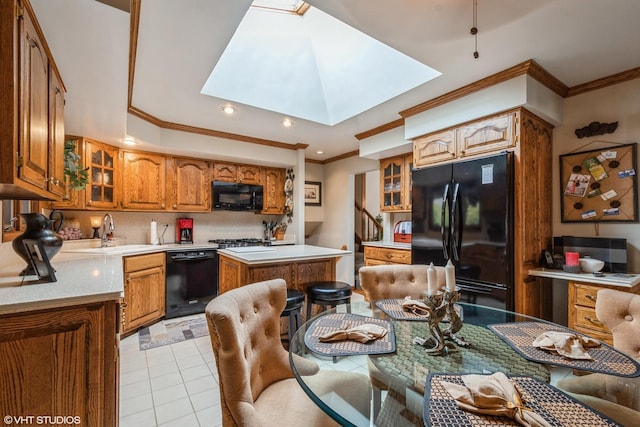 kitchen featuring a skylight, brown cabinetry, glass insert cabinets, light countertops, and black appliances