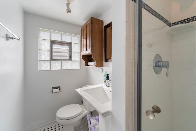 bathroom with toilet, baseboards, and tiled shower