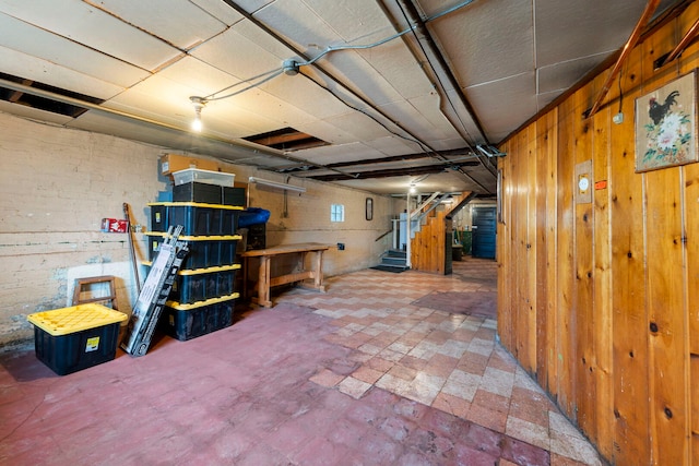 unfinished basement featuring wood walls and stairs