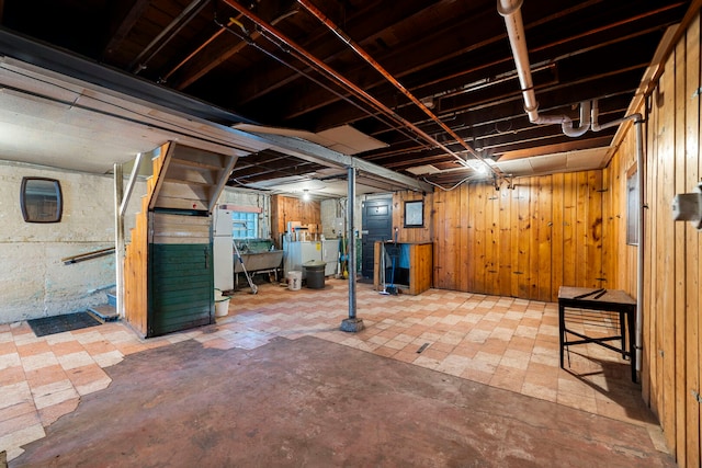 unfinished below grade area with freestanding refrigerator and wooden walls