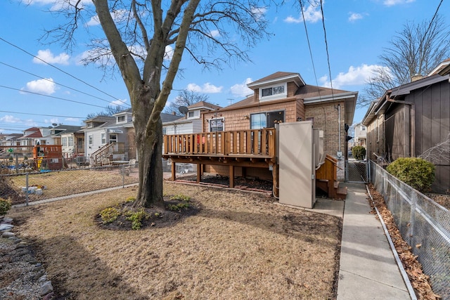 back of house featuring a deck, brick siding, fence, a residential view, and a gate