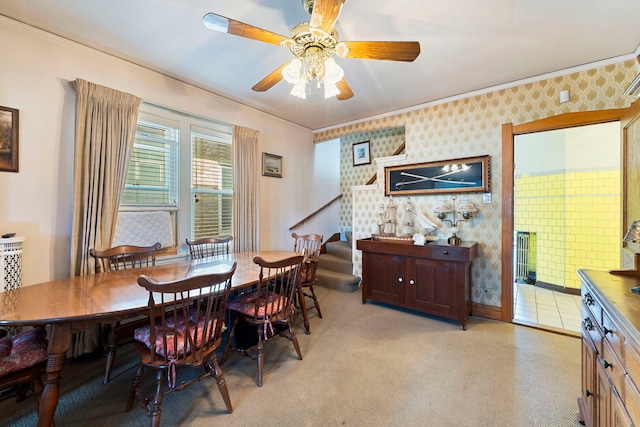 dining space with ornamental molding, light colored carpet, ceiling fan, and wallpapered walls