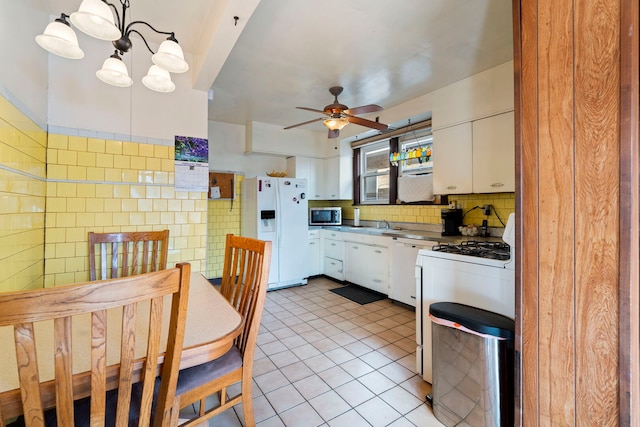 kitchen featuring white appliances, light tile patterned floors, white cabinetry, and tile walls