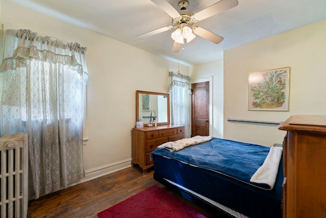 bedroom featuring radiator heating unit, wood finished floors, a ceiling fan, and baseboards