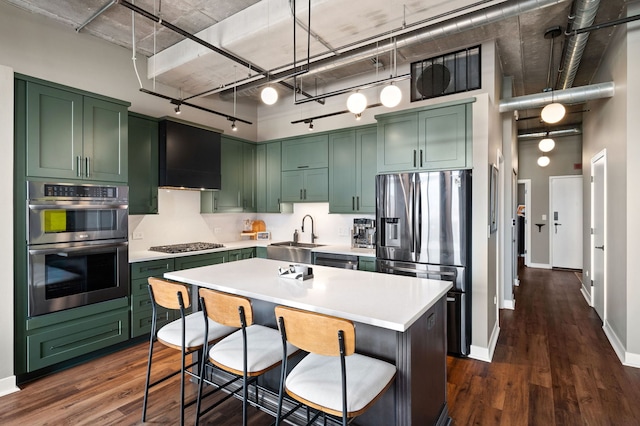 kitchen with a high ceiling, a sink, light countertops, appliances with stainless steel finishes, and a center island