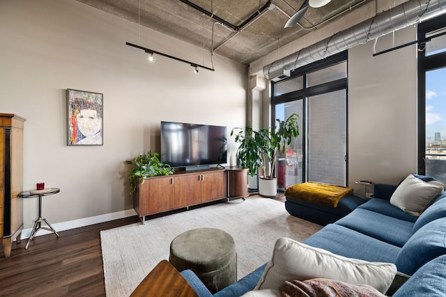 living room featuring track lighting, wood finished floors, and baseboards