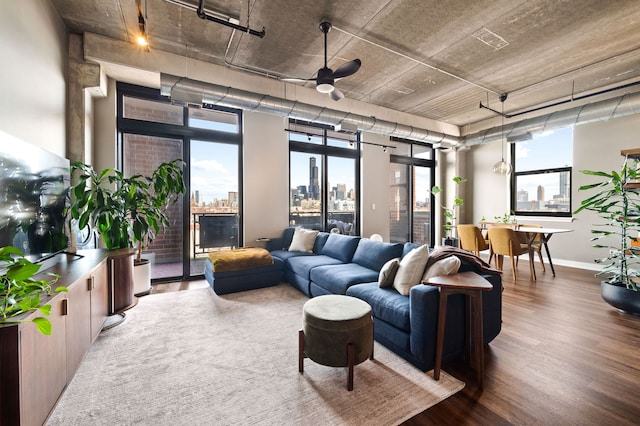 living area featuring baseboards, wood finished floors, a ceiling fan, and a city view