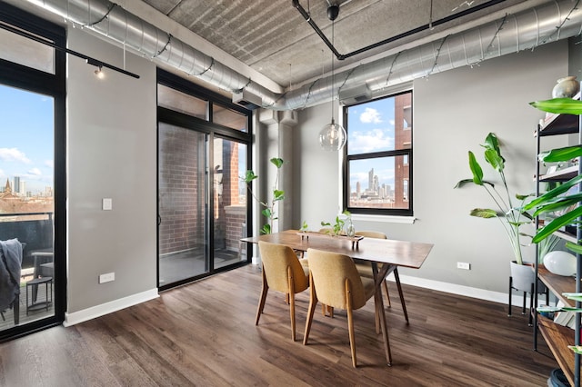 dining space featuring a view of city, dark wood-style flooring, and baseboards