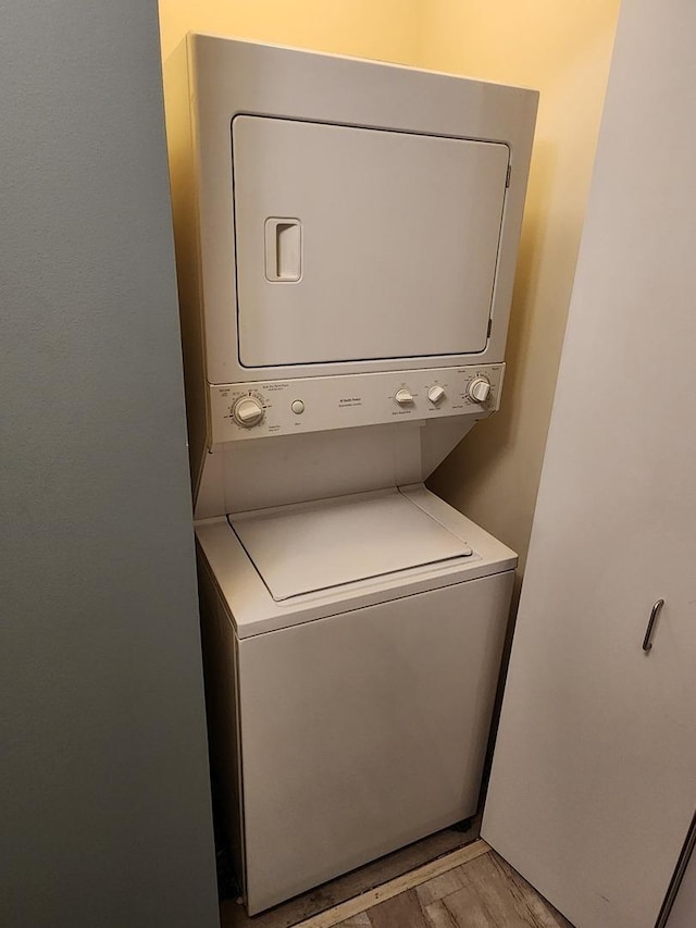 laundry room with stacked washer and dryer and light wood finished floors