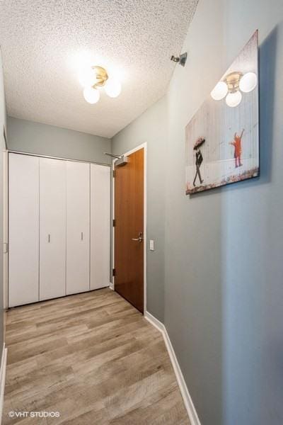 hallway with a textured ceiling, wood finished floors, and baseboards