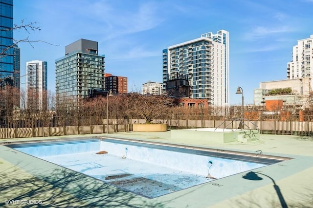 pool with a patio area, a view of city, and fence