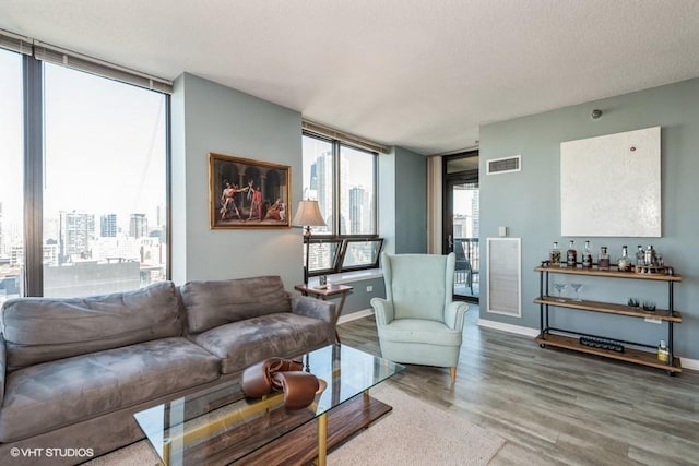 living area with baseboards, visible vents, and wood finished floors