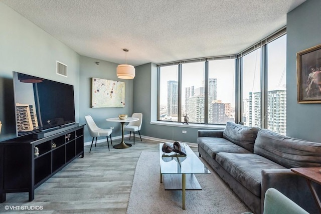 living area featuring a view of city, visible vents, a textured ceiling, wood finished floors, and baseboards