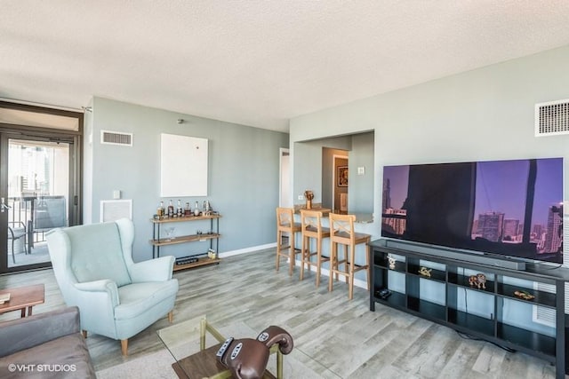 living room featuring visible vents, light wood-style flooring, and baseboards