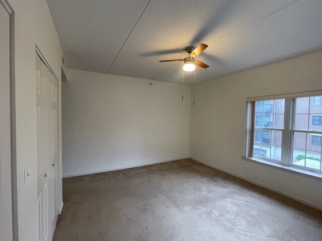 420 W Burlington Ave Unit 303, La Grange, IL 60525 - unfurnished bedroom with carpet, baseboards, a closet, a ceiling fan, and a textured ceiling