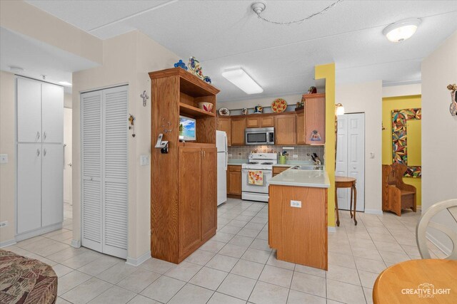 420 W Burlington Ave Unit 303, La Grange, IL 60525 - kitchen featuring white appliances, a sink, a peninsula, backsplash, and light countertops
