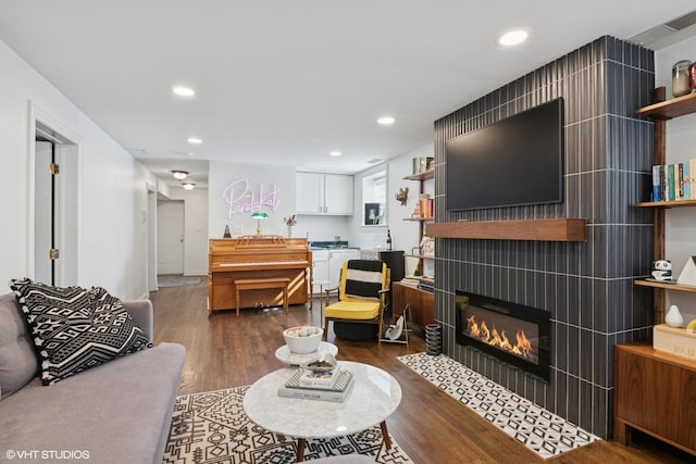 living area with recessed lighting, a tile fireplace, and dark wood-style flooring