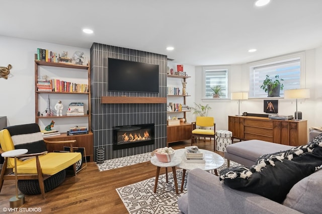 living area with recessed lighting, a large fireplace, and wood finished floors