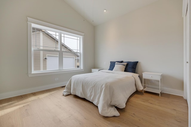 bedroom with light wood-type flooring, lofted ceiling, and baseboards