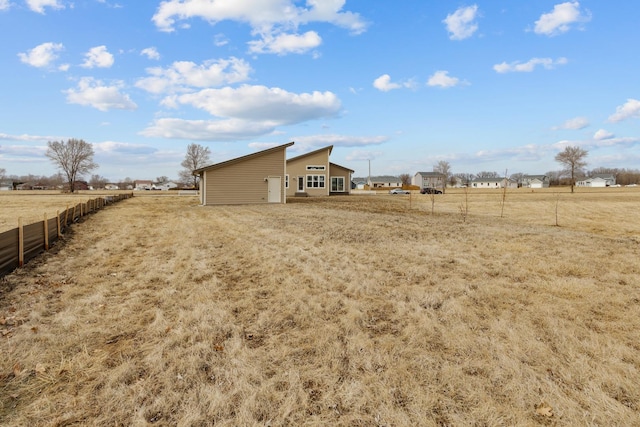 view of yard with fence and a rural view