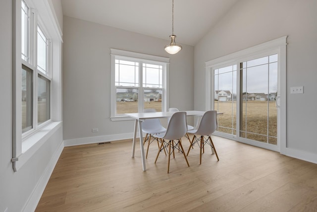 dining room with light wood-style floors, lofted ceiling, visible vents, and baseboards