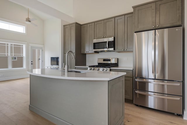 kitchen featuring ceiling fan, a sink, light countertops, appliances with stainless steel finishes, and light wood-type flooring