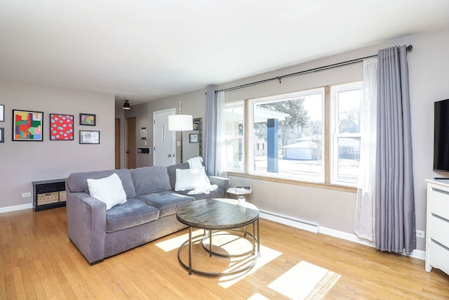 living room featuring a baseboard heating unit, light wood-type flooring, and baseboards