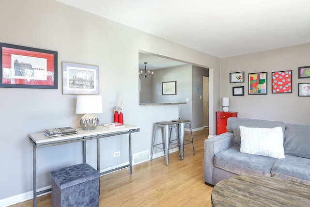 living room featuring visible vents, a notable chandelier, light wood-style flooring, and baseboards