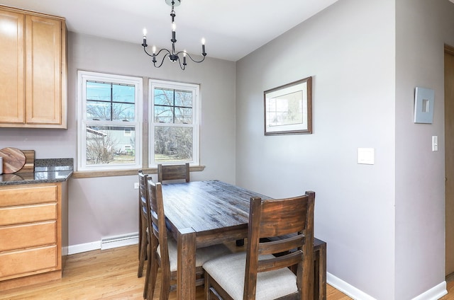 dining space featuring a notable chandelier, a baseboard heating unit, light wood finished floors, and baseboards