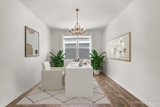 dining space with a chandelier, wood finished floors, and baseboards