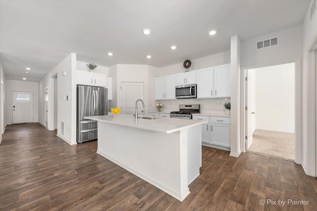 kitchen featuring stainless steel appliances, a sink, white cabinets, light countertops, and an island with sink