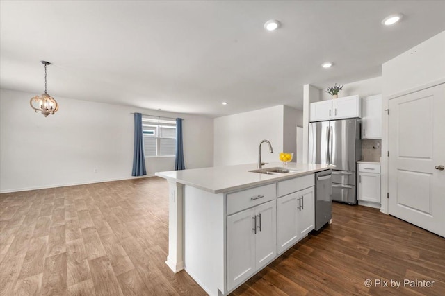 kitchen featuring appliances with stainless steel finishes, light countertops, a sink, and an island with sink