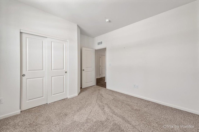 unfurnished bedroom with a closet, carpet flooring, visible vents, and baseboards