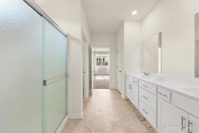 bathroom featuring double vanity, a stall shower, a sink, and baseboards