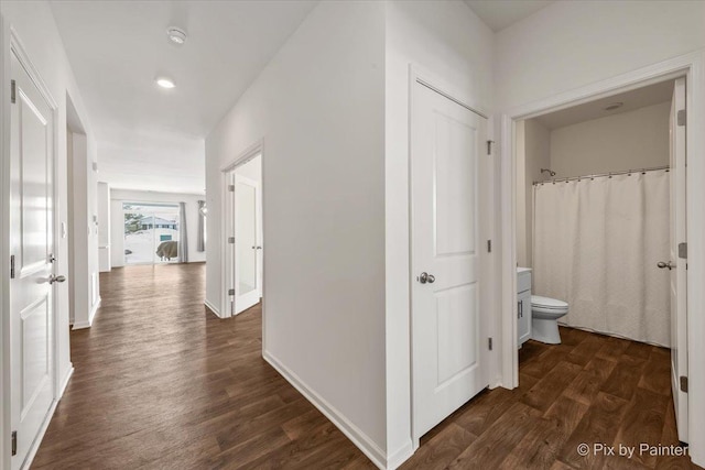 hall with dark wood-style flooring and baseboards