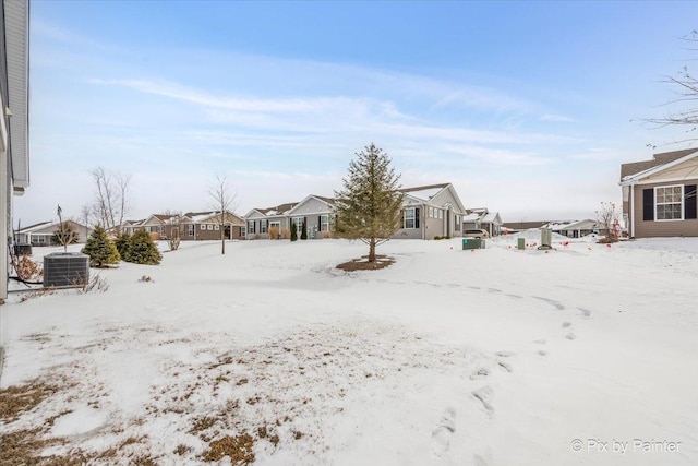 snowy yard featuring central air condition unit and a residential view