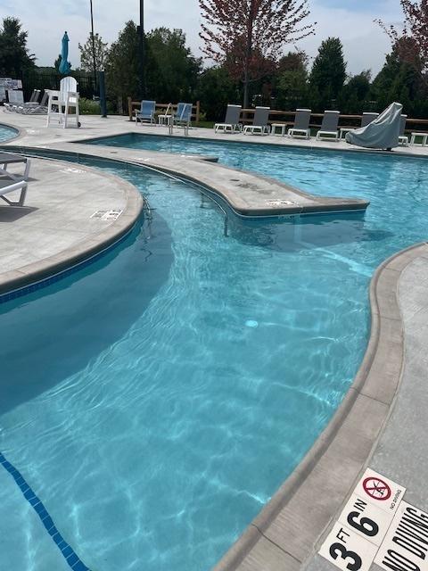 community pool with a water slide and a patio area