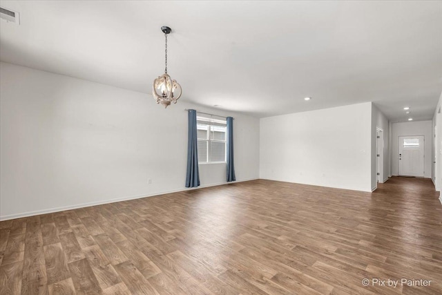 spare room featuring a chandelier, visible vents, light wood-style flooring, and recessed lighting