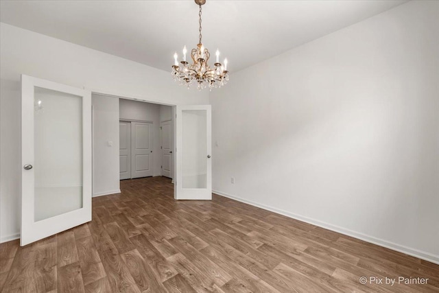 interior space with an inviting chandelier, baseboards, and wood finished floors