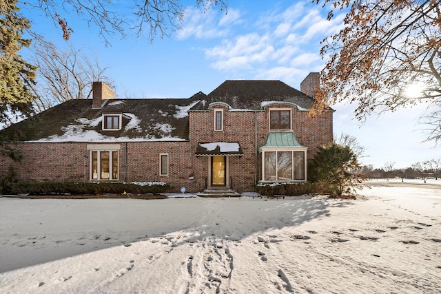 view of front of house with brick siding and a chimney