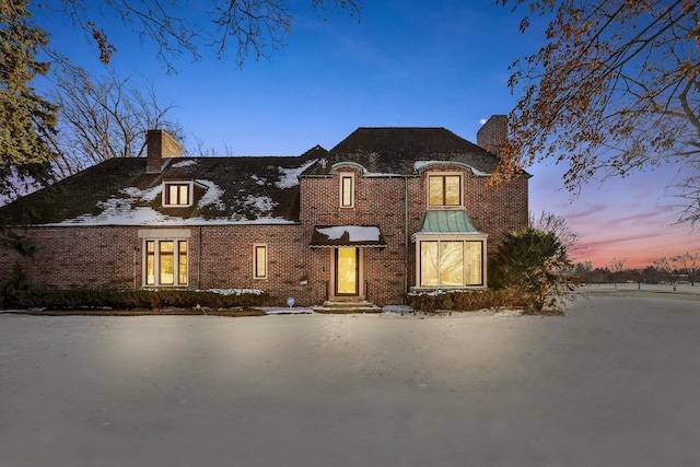 view of front of house with a chimney and brick siding