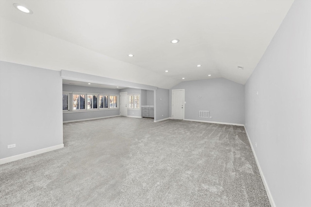 unfurnished living room featuring lofted ceiling, light carpet, and baseboards