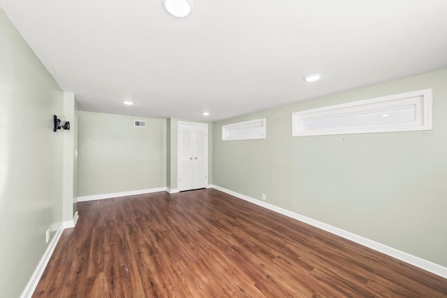 empty room featuring dark wood-style floors, visible vents, and baseboards