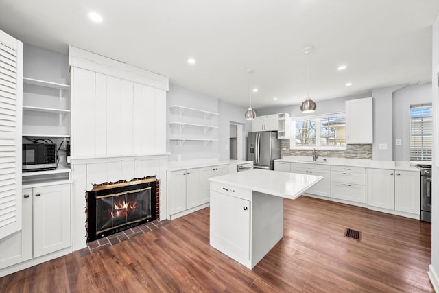 kitchen with white cabinets, a center island, stainless steel appliances, light countertops, and open shelves