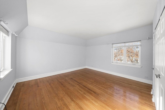 interior space featuring baseboards, vaulted ceiling, and wood finished floors